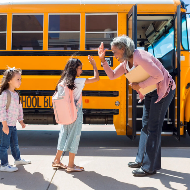 Child high-fiving educator before getting on school bus