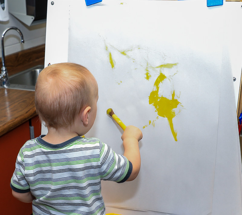 Toddler painting on an easel 