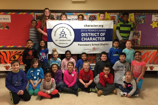 Students gather around a banner awarded for being a district of character