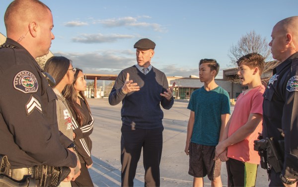 Dale Marsden talks with a group of students and two officers outside a school