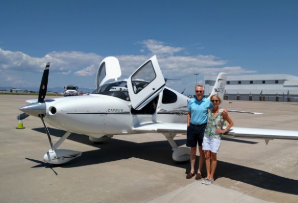 Deb Fallows poses with a man in front of a small airplane