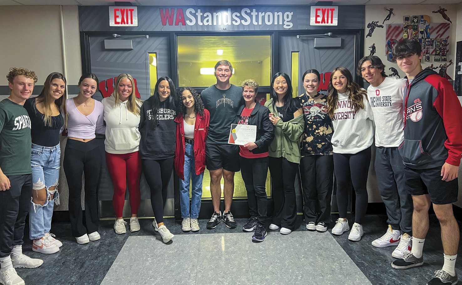 A large group of students stand together smiling at camera with their superintendent. 