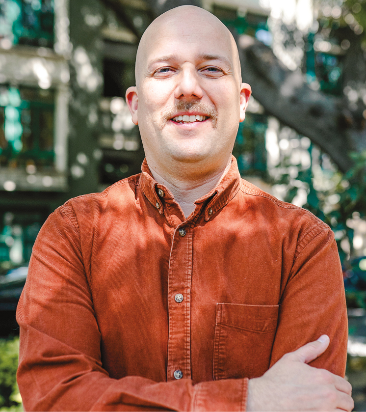 A man wearing a rust orange shirt outside headshot