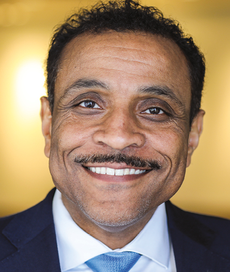 A man with black hair and mustache wearing a suit headshot