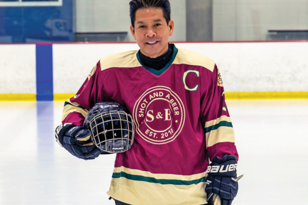 Man holding hocket helmet in uniform on the ice