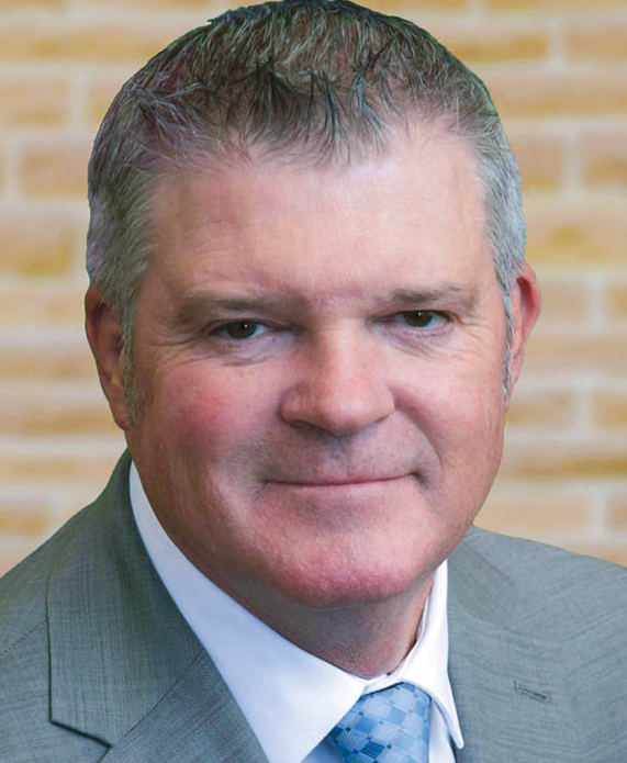 A man's headshot wearing a gray suit and blue tie