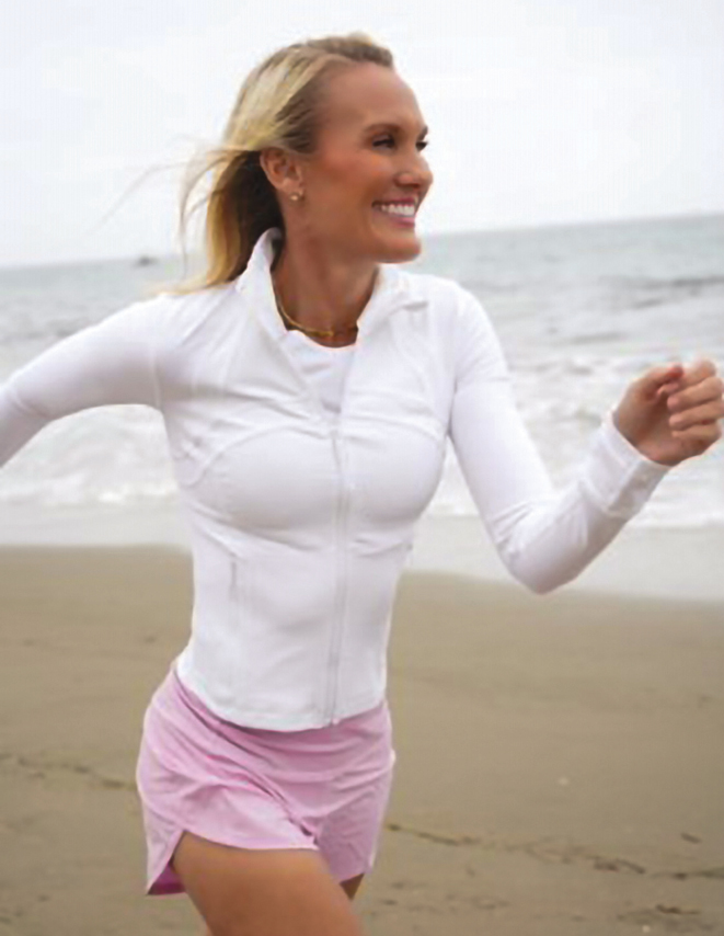 A woman running on the beach smiling weraing Lululemon clothes