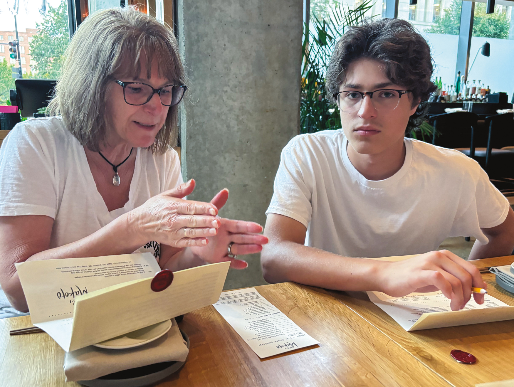 A woman sitting with her son at a table, both wearing white