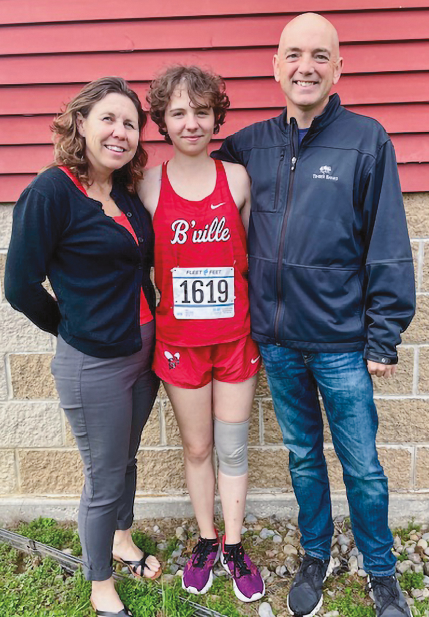 A woman and man standing with their child, who is wearing running clothesT