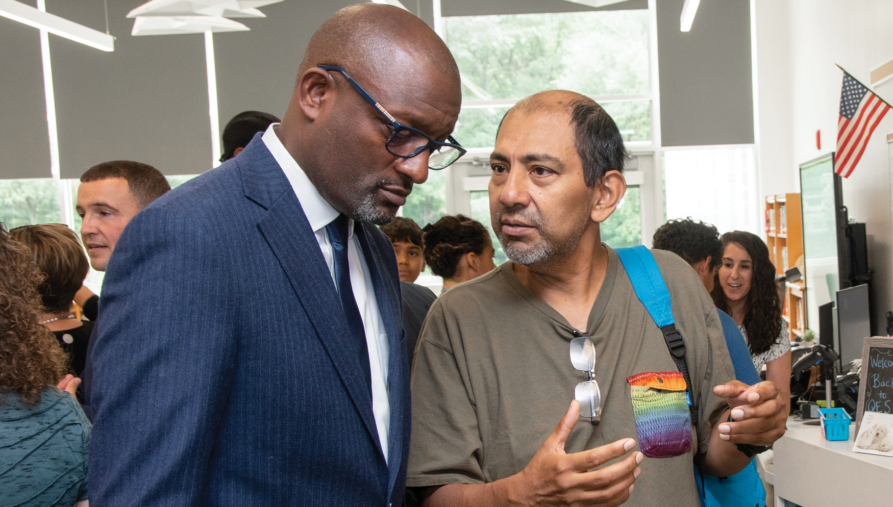 A superintendent in a suit listening intently to a parent talking