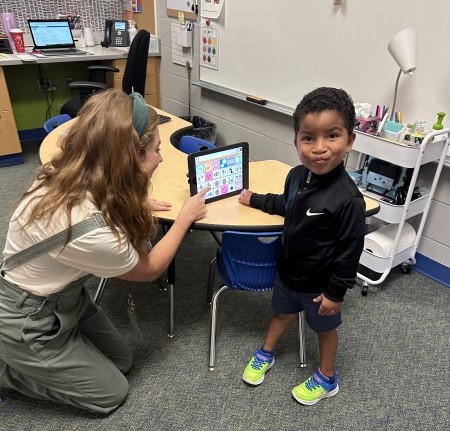 Preschooler works with teacher on tablet